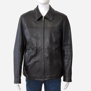 May include: A black leather jacket featuring a collared neckline and a full-length zip. The jacket has two front pockets and a classic, tailored fit. The leather appears smooth with subtle texture variations.