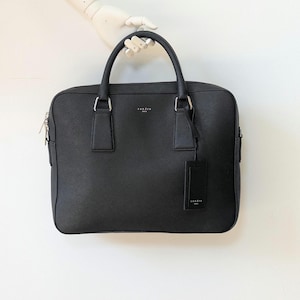 Porte-documents pour ordinateur portable en cuir noir Sandro Saffiano Downtown Paris avec garnitures argentées et poches intérieures Bandoulière non incluse.