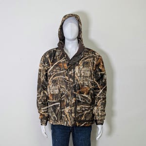 May include: A camouflage hooded jacket with a brown collar and the word "ROCKY" on the chest. The jacket features a full-length zipper, multiple pockets, and a pattern of brown, tan, and green. The jacket is displayed on a mannequin.