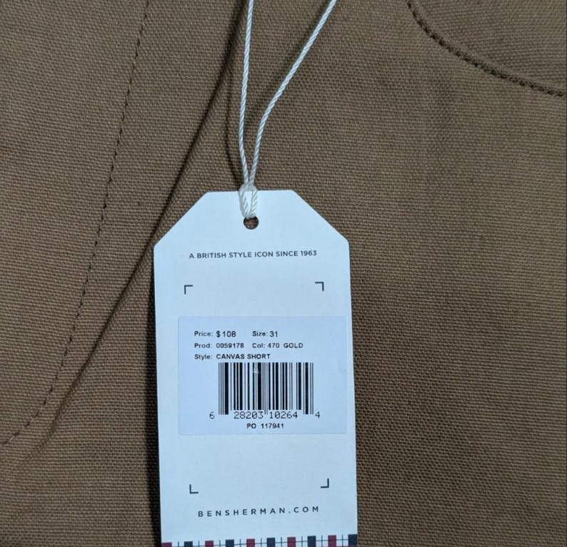 May include: A clothing tag for canvas shorts, with the text "A BRITISH STYLE ICON SINCE 1963". The tag displays the price, size 31, product and color codes, and the style "CANVAS SHORT". The brand name is BENSHERMAN.COM.