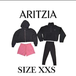 May include: A black zip-up hoodie, a black fleece jacket, pink shorts, and black leggings are displayed. The brand name "ARITZIA" and size "XXS" are printed in black capital letters.