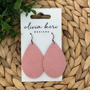 May include: A pair of pink leather teardrop earrings with a textured finish. The earrings are on a white card with the text "olivia keri DESIGNS".