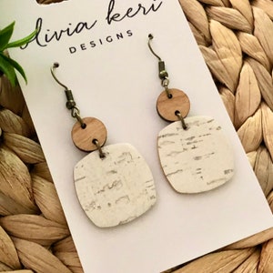 Puede incluir: Un par de pendientes de madera blanca y marr&oacute;n con forma cuadrada y un acento redondo. Los pendientes est&aacute;n en una tarjeta blanca con el texto "livia kerri DESIGNS".