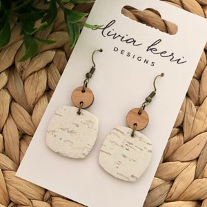 Puede incluir: Un par de pendientes de corcho blanco y marr&oacute;n con forma cuadrada y un acento redondo de madera. Los pendientes est&aacute;n en una tarjeta blanca con el texto "livia kerr designs".