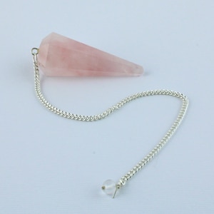 Könnte beinhalten: Ein rosa Rosenquarz-Pendel mit einer silbernen Kette und einer klaren Kristallperle am Ende.