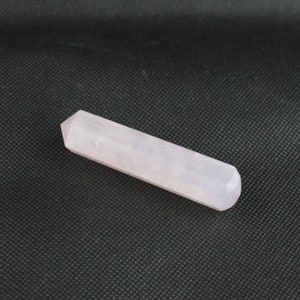 Peut inclure: Une baguette en cristal rose pâle lisse avec une extrémité pointue et des bords arrondis.