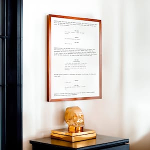 May include: A framed script from the film "Star Wars: Episode VI - Return of the Jedi" with a gold skull sculpture on a wooden table. The script includes dialogue from the characters Obi-Wan Kenobi, Darth Vader, and Luke Skywalker.