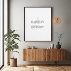 May include: A framed print with black border, featuring text about the Federalist Papers. The print hangs above a wooden cabinet with decorative items. A potted plant and a hanging light fixture are also visible.