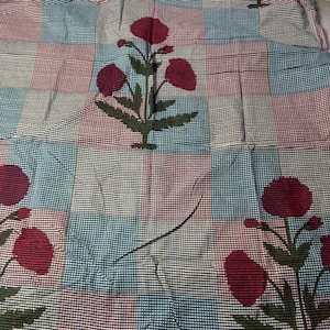 Peut inclure: Un tissu à motifs avec un motif quadrillé en bleu sarcelle, bordeaux et blanc cassé. Le tissu est orné de motifs floraux stylisés en bordeaux et vert, créant une esthétique vintage. Le tissu est probablement utilisé pour la décoration intérieure ou l'habillement.