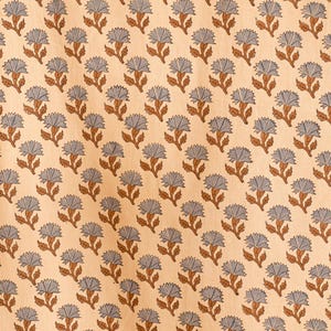 May include: A light peach-colored fabric featuring a repeating pattern of small, stylized flowers. Each flower has light blue petals and a brown stem with two leaves, arranged in a consistent grid-like layout across the entire surface.