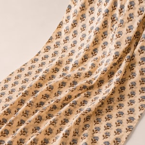 It is a hand block printed cotton fabric in beige colour with a design of grey and brown flower all over. Fabric is used for bohemian dress making for women as well as for home decor creation products like curtains.