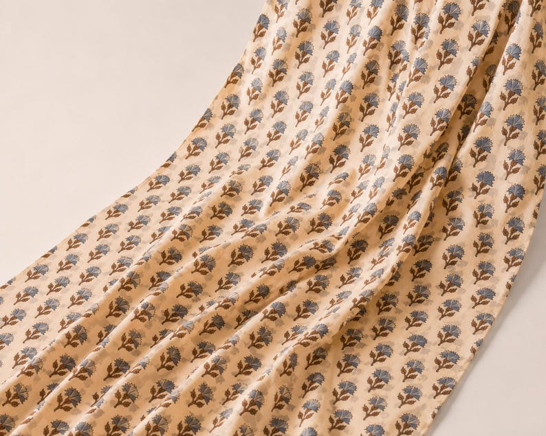It is a hand block printed cotton fabric in beige colour with a design of grey and brown flower all over. Fabric is used for bohemian dress making for women as well as for home decor creation products like curtains.