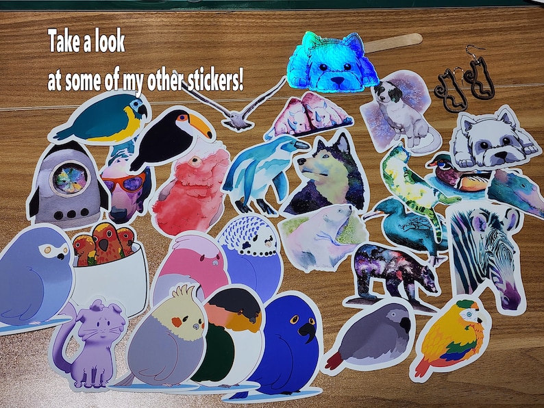May include: A collection of colorful stickers featuring various animals, including birds, penguins, a husky, a zebra, a bear, and a cat. The stickers are on a wooden surface. The text "Take a look at some of my other stickers!" is visible in the top left corner of the image.