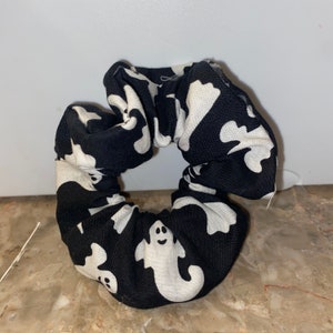 Op de afbeelding: Een zwarte scrunchie met een wit spookpatroon.