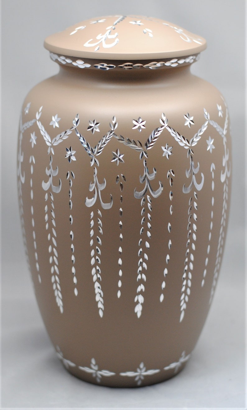 May include: A brown ceramic urn with a silver floral design. The urn has a lid and is decorated with a repeating pattern of flowers and leaves.