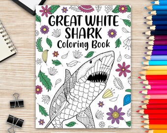 May include: A coloring book titled "Great White Shark Coloring Book" featuring a detailed illustration of a shark with open jaws. The cover is decorated with floral and leaf designs. A set of colored pencils is visible on the right.