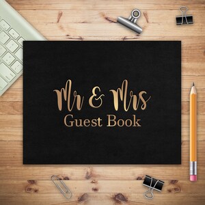 May include: Black guest book with gold foil lettering that reads "Mr & Mrs Guest Book".