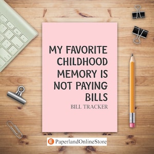 May include: A pink card with the text "My favorite childhood memory is not paying bills" and the words "Bill Tracker" below. The card is on a wooden surface with a pencil, paper clips, and a keyboard.
