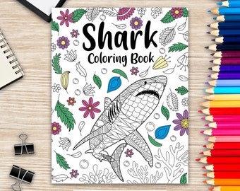 May include: A black and white coloring book featuring a detailed illustration of a shark with a floral and leaf pattern surrounding it. The title of the book is "Shark Coloring Book".