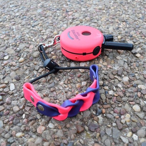 May include: Pink and black dog training collar with a remote control. The remote control has the text "PRO EDUCATION" on it.