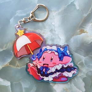 May include: A pink cartoon character keychain with a red and white umbrella and a gold-colored star. The character is wearing a blue and white dress and has blue bows. The keychain has a silver-colored clasp.