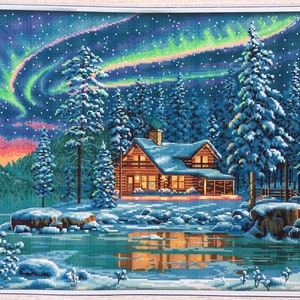 May include: A cross-stitch artwork depicting a cosy cabin nestled in a snowy forest under a vibrant aurora borealis. The cabin has a warm glow emanating from its windows, and the sky is filled with twinkling stars.