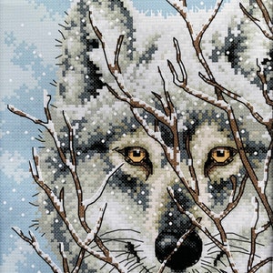 May include: A white wolf with brown eyes peers through a snowy forest of bare branches. The wolf's fur is covered in snow, and the background is a light blue sky with white snowflakes.