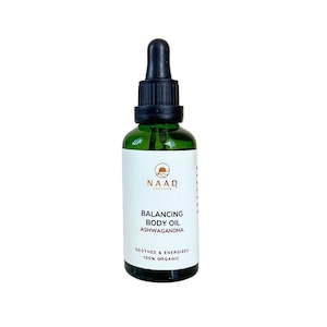 May include: A green glass bottle with a black dropper top. The label reads "NAAD Organics Balancing Body Oil Ashwagandha Soothes & Energises 100% Organic"