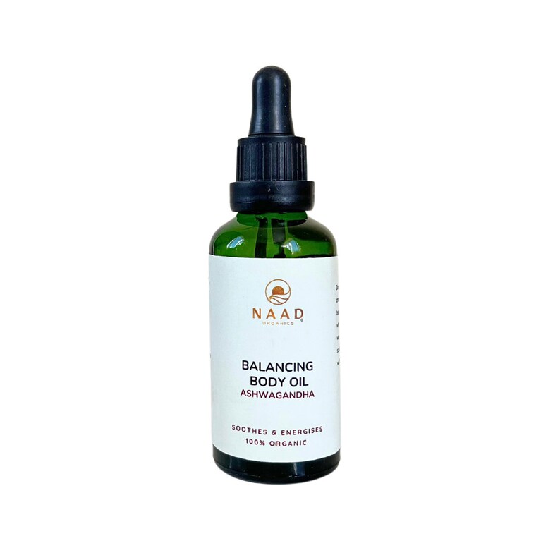 May include: A green glass bottle with a black dropper top. The label reads "NAAD Organics Balancing Body Oil Ashwagandha Soothes & Energises 100% Organic"