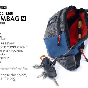 May include: A gray and blue bum bag with a red interior, featuring a key leash and pen holder. The bag is water-resistant and has three zippered compartments. The text on the bag reads "JABOI 2.5L BUMBAG M".