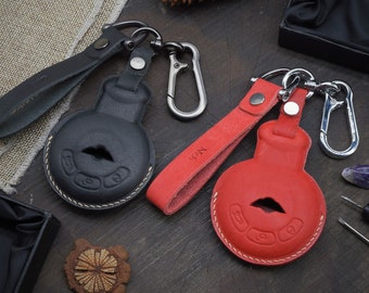May include: Two leather keychains with metal rings and loops. One keychain is black with a white stitched design and the other is red with a white stitched design.