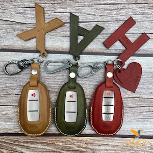 May include: Leather keychains in brown, green, and red, each with a matching key fob cover. The keychains feature personalized name tags: "Xavi", "Alecin", "Hugo", and "Alice". The key fobs have silver buttons and a car logo.