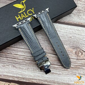 May include: Two gray leather watch bands with a textured pattern and a silver buckle. The bands are on a black box with the word "HALCY" printed on it.