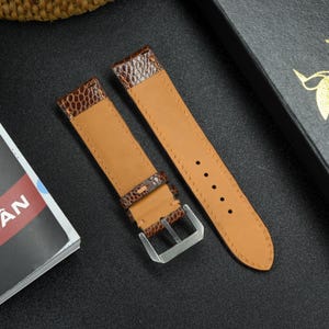 May include: Two brown leather watch straps with stitching detail. One strap has a buckle and the other has a plain end.