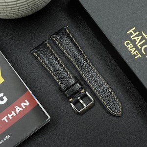 May include: Two black leather watch straps with yellow stitching. The straps are on a black surface. HALC CRAFT is printed on a black box in the background.