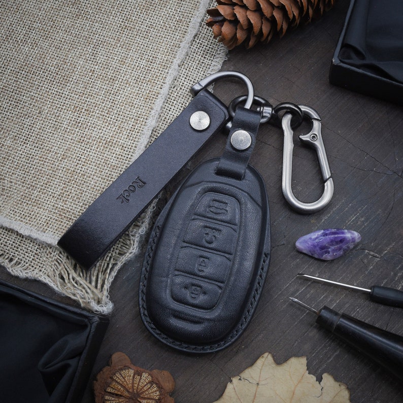 May include: Black leather key fob with a silver key ring and a black leather strap with the word "Rock" embossed on it.