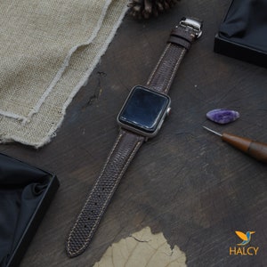 May include: A brown leather watch band with a textured pattern. The band is attached to a silver Apple Watch.