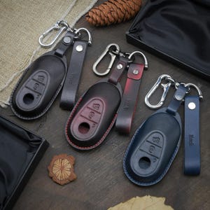 May include: Three leather key fobs with key rings. The key fobs are black, red, and blue. The key fobs have the word "Alfa" embossed on them.