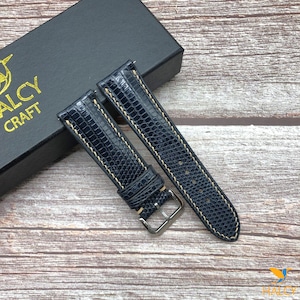 Peut inclure: Deux bracelets de montre en cuir bleu foncé avec des coutures blanches. Les bracelets sont disposés sur une surface en bois.