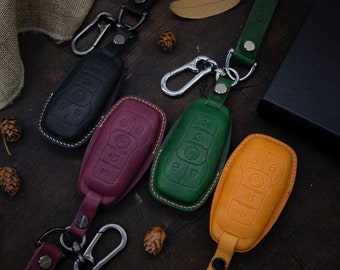 May include: Four leather keychains with different colored key covers. The key covers are black, burgundy, green, and yellow. Each keychain has a silver metal hook.