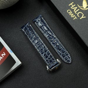 May include: Two blue alligator leather watch straps with white stitching. The straps have a silver buckle and are made by Halcy Craft.