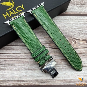 May include: Two green leather watch bands with white stitching and silver clasps. The bands are designed for Apple Watches.