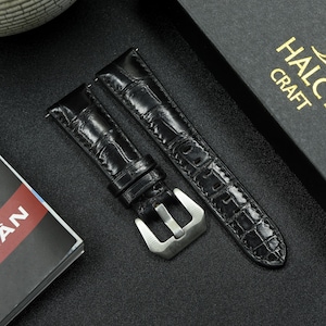 May include: Two black leather watch straps with a crocodile pattern. One strap has a silver buckle.