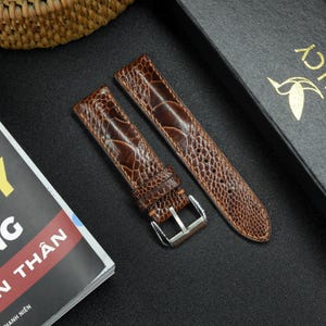 A detailed shot of the texture of a brown ostrich leg leather watch strap with natural grains, showing its unique pattern and stitching