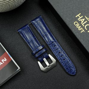May include: Two blue leather watch straps with a silver buckle. The straps have a crocodile pattern.