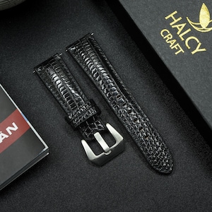 May include: Black watch straps with a textured, reptile-like pattern. The straps have a silver-colored buckle. The box in the background has the text "HALCY CRAFT".