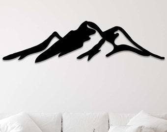 May include: A black metal silhouette of a mountain range wall decor hanging above a white couch and a woven rug.