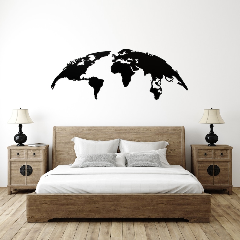 May include: A black world map wall decal above a wooden bed frame. The bedroom features two matching wooden nightstands with lamps. The bed has white bedding and pillows. The room has a neutral color palette.