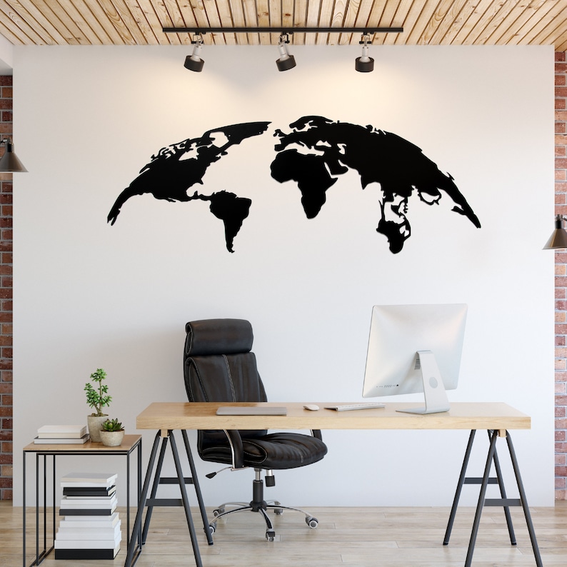 May include: A black world map wall decal is mounted on a white wall above a desk. The office space includes a wooden desk, black leather chair, and a small side table with a plant. The room has a modern, minimalist design.