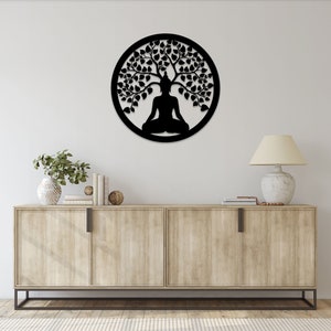 May include: A black metal wall art piece featuring a meditating Buddha figure under a tree, enclosed within a circular frame. The design is a silhouette, with intricate details of leaves and branches. This decorative piece is suitable for meditation spaces or home decor.
